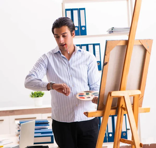 Jovem e bonito funcionário desfrutando de pintura no escritório — Fotografia de Stock