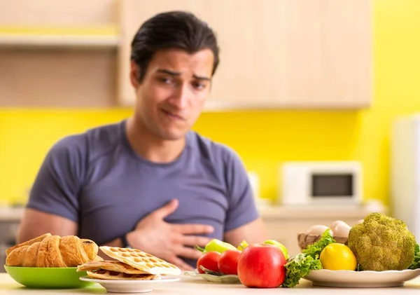 Homem tendo escolha difícil entre alimentos saudáveis e não saudáveis — Fotografia de Stock