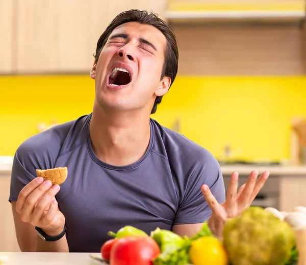 Man having hard choice between healthy and unhealthy food