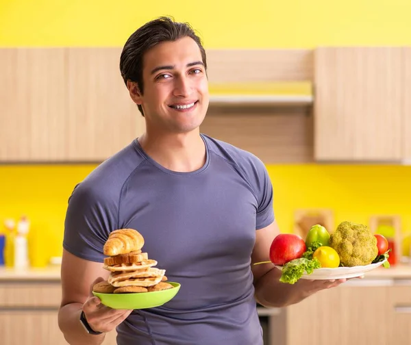 Homem tendo escolha difícil entre alimentos saudáveis e não saudáveis — Fotografia de Stock