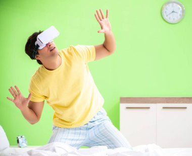 Yatak odasında sanal gözlüklü genç adam.