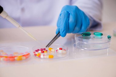 Uyuşturucu sentezi konseptinde genç erkek laboratuvar asistanı
