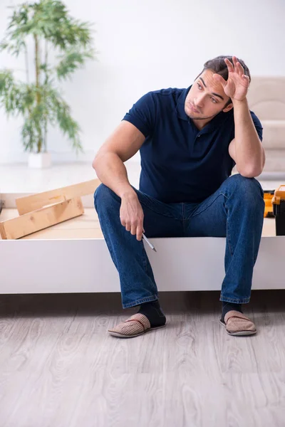 Jovem empreiteiro masculino instalando móveis em casa — Fotografia de Stock