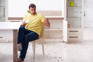 Genç adam ve evde bir sürü hamamböceği var.