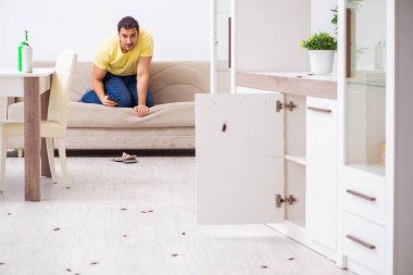 Genç adam ve evde bir sürü hamamböceği var.