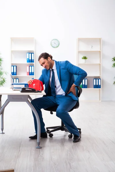 Joven empleado en concepto de primeros auxilios — Foto de Stock