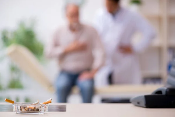 Sigara karşıtı genç erkek doktor ve yaşlı hasta — Stok fotoğraf