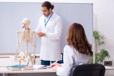 Genç erkek öğretmen doktor, iskelet ve kız öğrenci.
