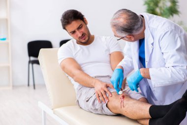 Yaralı adam ilk yardım konseptinde yaşlı doktoru ziyaret ediyor.