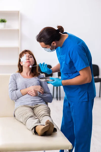 Young head injured woman visiting young male doctor — Stockfoto