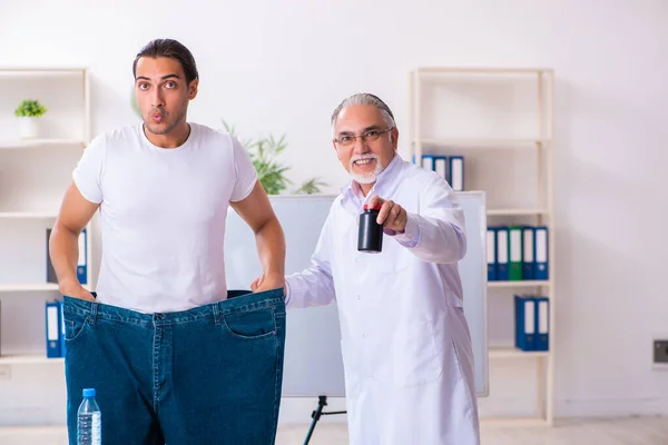 Doctor dietician and happy patient wearing large trousers — Φωτογραφία Αρχείου