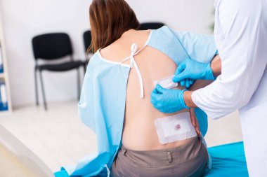 Yaralı genç kadın genç erkek doktoru ziyaret ediyor.