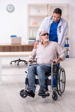 Yaşlı kör adam genç erkek doktoru ziyaret ediyor.