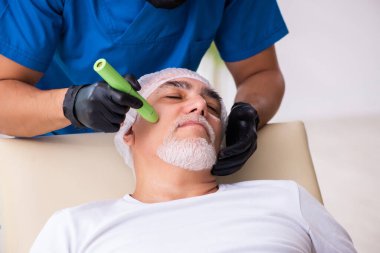 Yaşlı adam estetik ameliyat için erkek doktoru ziyaret ediyor.