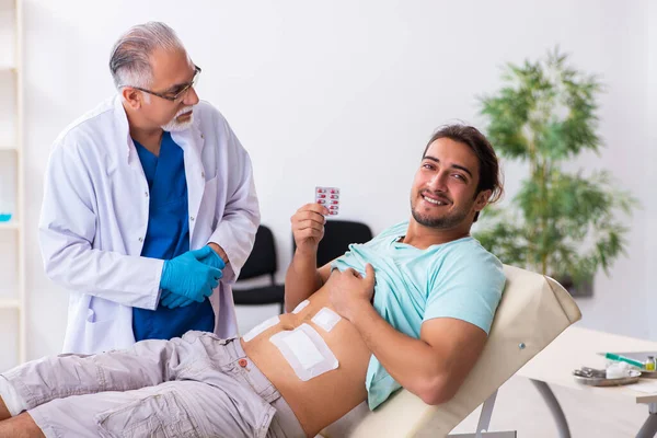 Verletzter junger Mann besucht erfahrenen Arzt — Stockfoto