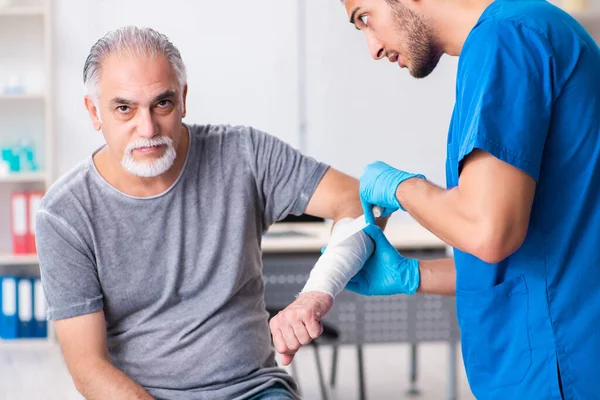 Junger Arzt und alter Patient im Erste-Hilfe-Konzept — Stockfoto