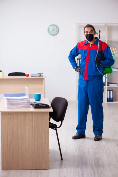 Young male contractor disinfecting office — Stock Photo, Image