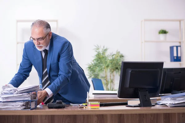 Velho empregado masculino e excesso de trabalho no escritório — Fotografia de Stock