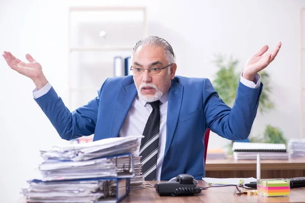 Velho empregado masculino e excesso de trabalho no escritório — Fotografia de Stock