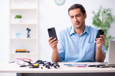 Cep telefonunu tamir eden genç bir teknisyen.