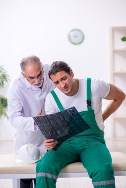 Genç erkek müteahhit yaşlı doktoru ziyaret ediyor.