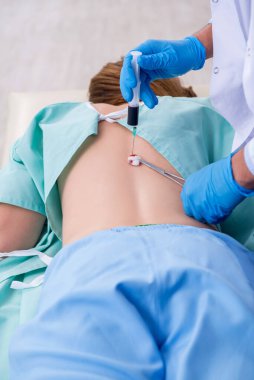 Genç sırtı yaralı kadın, erkek doktor masörünü ziyaret ediyor.