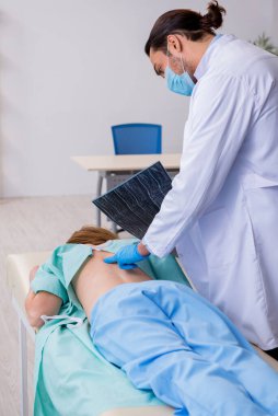 Genç sırtı yaralı kadın, erkek doktor masörünü ziyaret ediyor.