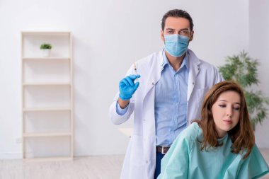 Genç sırtı yaralı kadın, erkek doktor masörünü ziyaret ediyor.