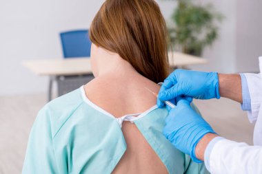 Genç sırtı yaralı kadın, erkek doktor masörünü ziyaret ediyor.