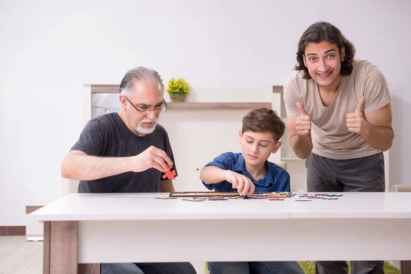 Tres generaciones de familia jugando rompecabezas juego — Foto de Stock