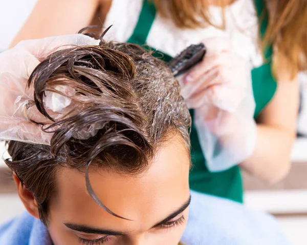 Peluquero mujer aplicando tinte al cabello del hombre —  Fotos de Stock
