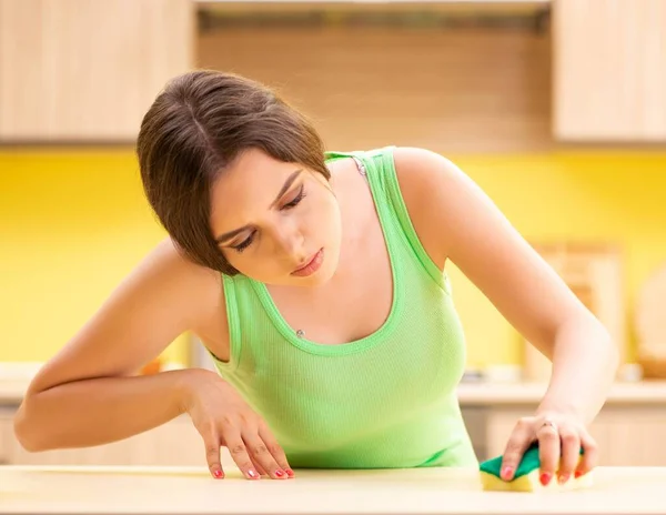 Jovem mulher beatifull polimento mesa na cozinha — Fotografia de Stock