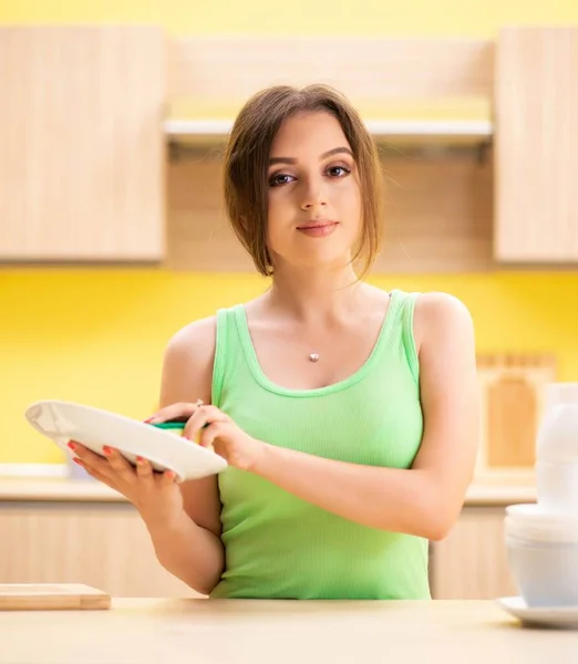 Jeune femme nettoyage et lavage de la vaisselle dans la cuisine — Photo