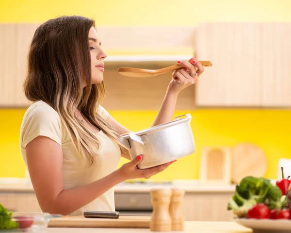 Young woman cooking soup in kitchen at home — Stock Photo, Image