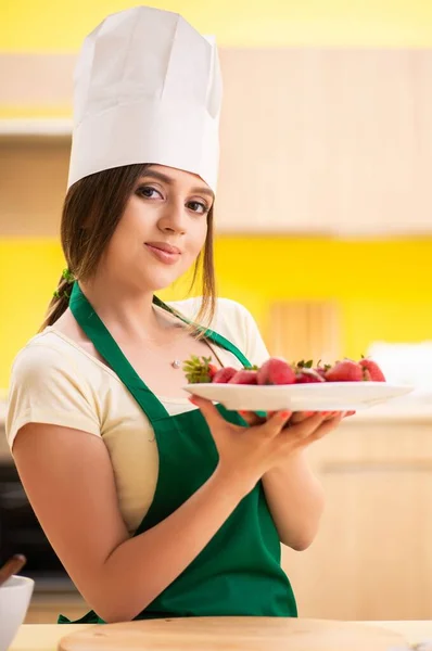 Молодая женщина-повар ест клубнику — стоковое фото
