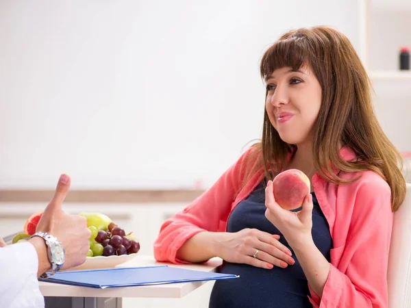 Mujer embarazada visitando al médico discutiendo dieta saludable — Foto de Stock