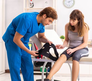 Genç bayan hasta erkek doktor travmatoloğu ziyaret ediyor.