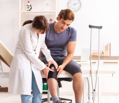 Genç erkek hasta, kadın doktor travmatoloğu ziyaret ediyor.
