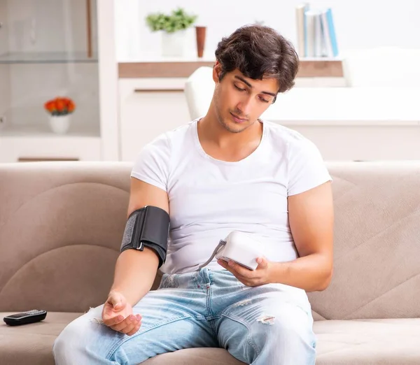 Young man measuring blood pressure at home — Stock Photo, Image