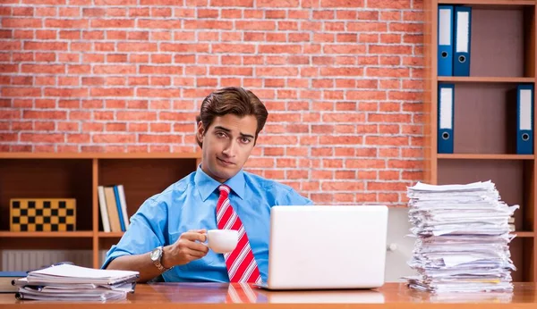 Young employee with excessive work sitting at the office — Stock Photo, Image