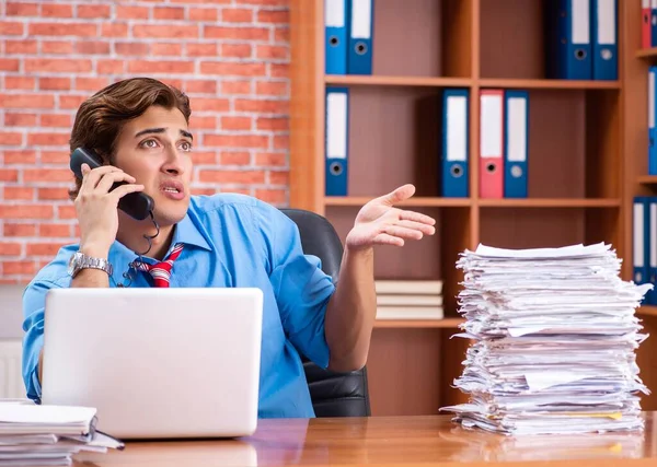 Young employee with excessive work sitting at the office