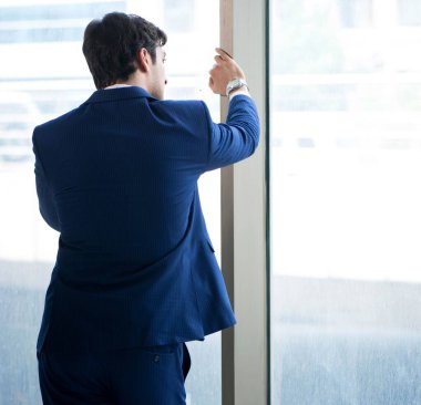 Genç yakışıklı işadamı pencerede duruyor.