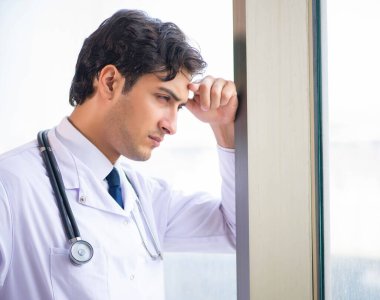 Genç yakışıklı doktor pencerede duruyor.