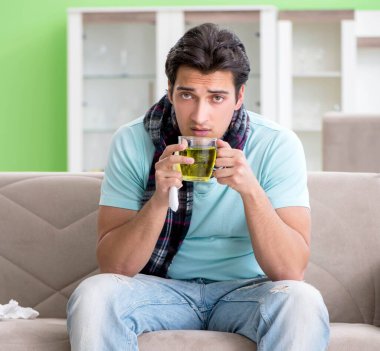 Evde hastalıktan muzdarip genç yakışıklı bir adam.