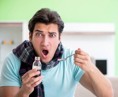 Evde hastalıktan muzdarip genç yakışıklı bir adam.