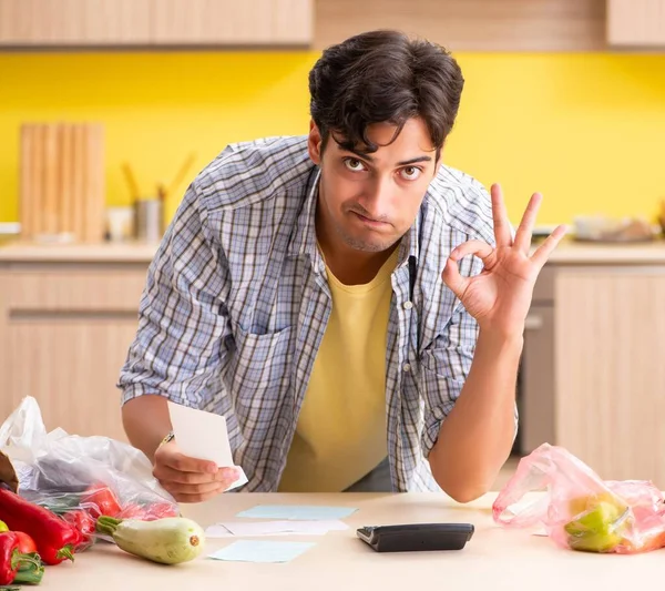 Молодий чоловік розраховує витримки для овочів на кухні — стокове фото