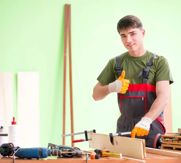 Молодой плотник, работающий в мастерской — стоковое фото