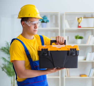 Genç müteahhit ofiste tamirat yapıyor.