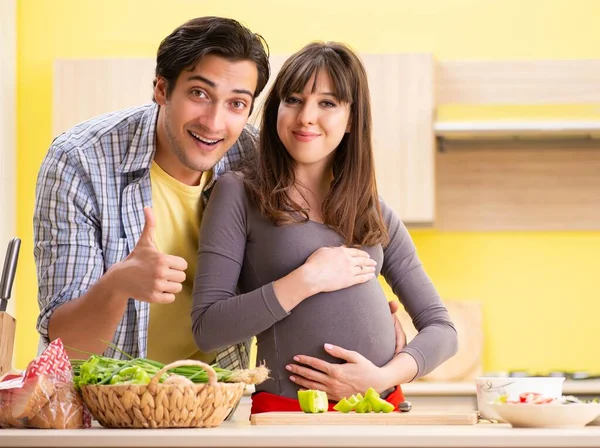 Hombre y mujer embarazada preparando ensalada en la cocina —  Fotos de Stock