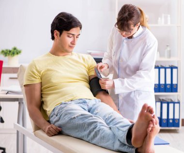 Genç doktor hastaların tansiyonunu ölçüyor.